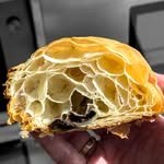 Croissant abierto por la mitad, sostenido en la mano.